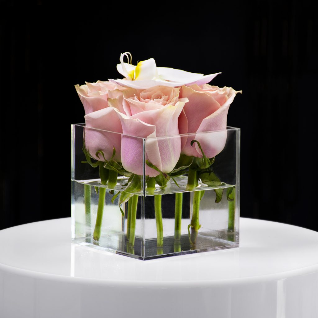 Clear acrylic vases with pink flowers and clear acrylic picture frame with image of young girl.