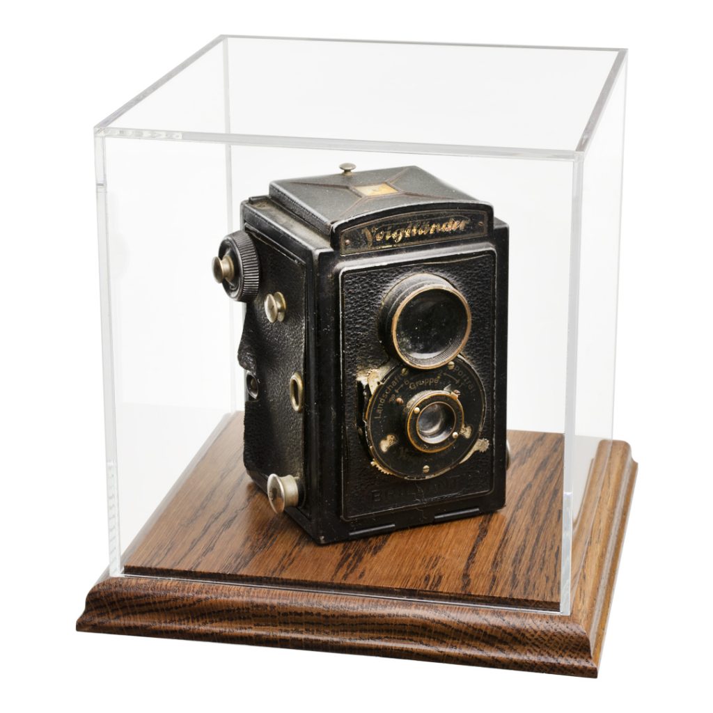 Antique camera in acrylic display box with wood base.
