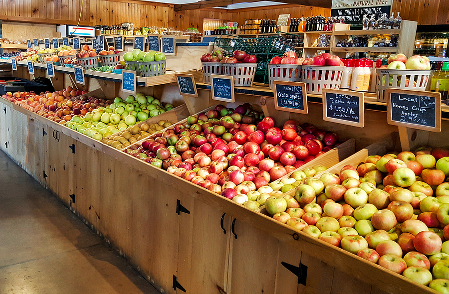 Variety of apples displayed in a grocery store on wood shelving.