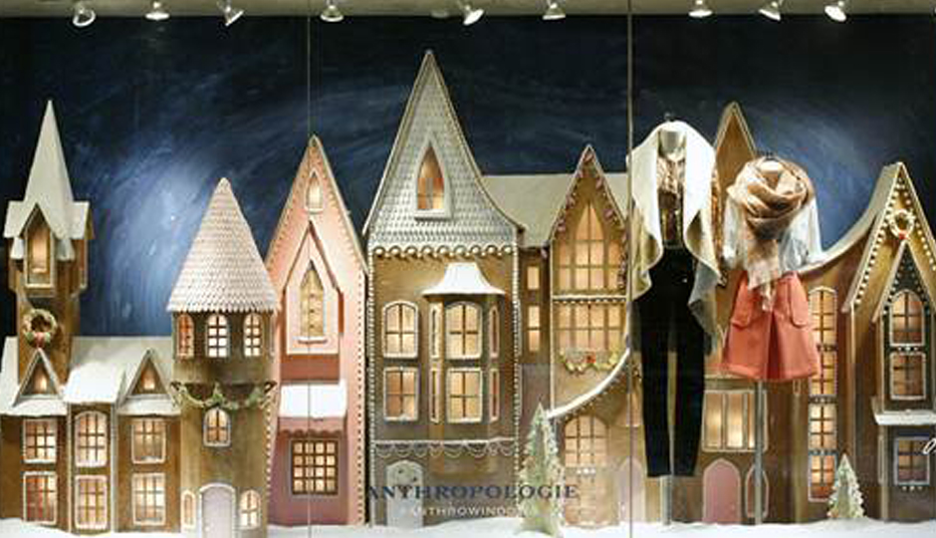 Anthropologie holiday window display with mini buildings behind two mannequins.