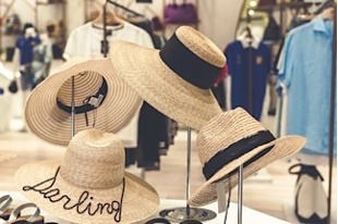 Straw hats with black bands on display stands in store.