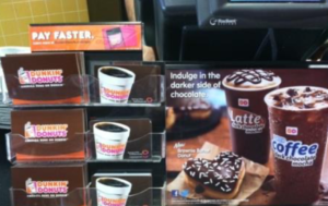 Dunkin' Donuts checkout counter with gift card displays and sign displays in front of the cash register.