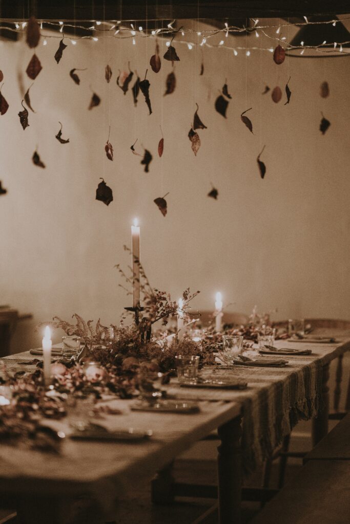 Fall tablescape with dim lighting and leaves hanging from ceiling.