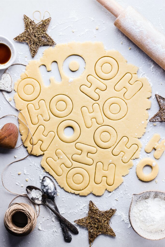 Holiday cookie dough rolled out surrounded by rustic holiday items.