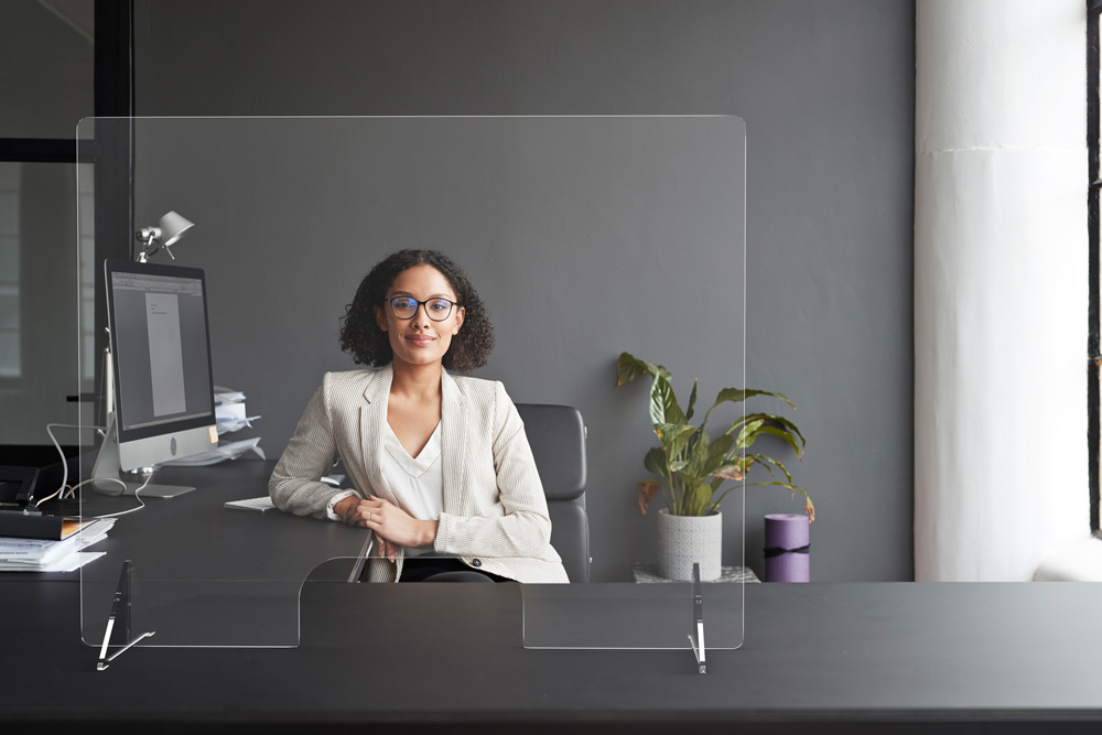 woman at desk with plexiglass shield with opening