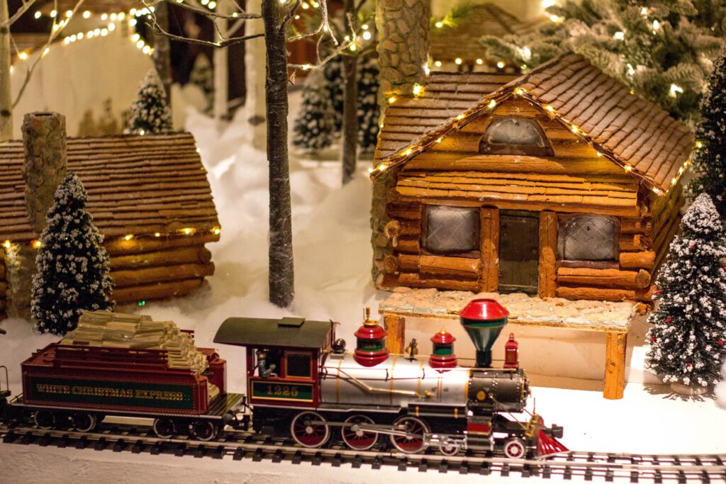 model train in Christmas display in front of model log cabin