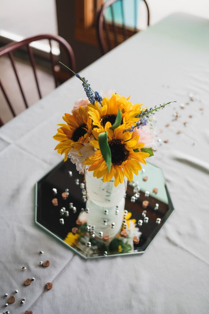 Acrylic mirror below a vase with sunflowers on a table.