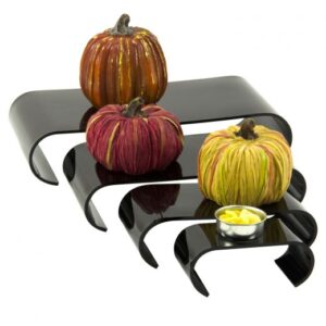 U-shaped black acrylic risers holding decorative pumpkins.