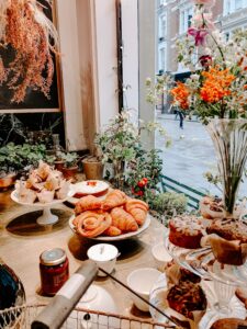 A window display of cupcake display stands and cake riser pedestals brimming with pastries entice and invite patrons inside. 