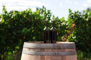 Barrel display with two wine bottles on top in vineyard.