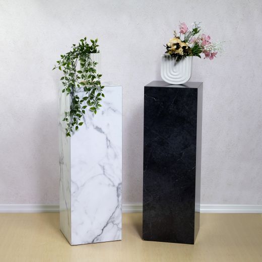 Two luxury laminate pedestals in black and white marble with a plant and flowers on top.