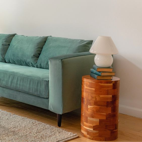 Lighted wood display pedestal holding a black vase.