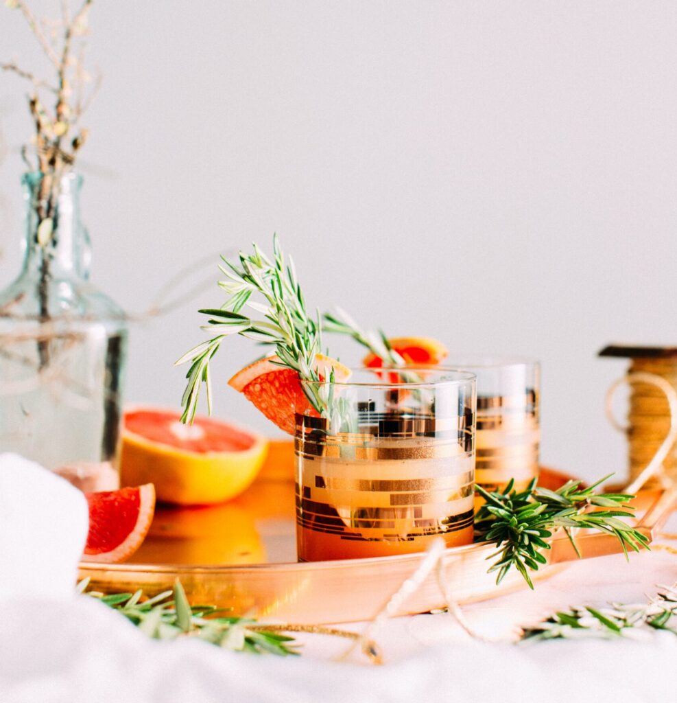 Cocktail on a gold tray with thyme and grapefruit.