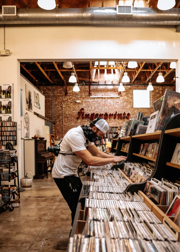 Man with face covering looking through a record display in a music store