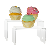 Two clear acrylic risers with one green, pink and white frosted cupcakes