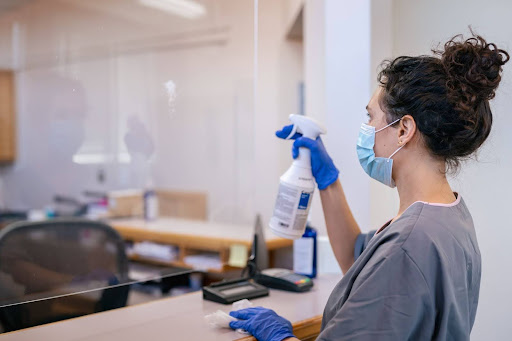 ALT Text: Woman cleaning plexiglass shield 